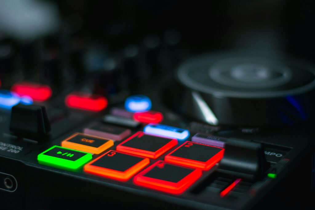 Close-up of colorful illuminated DJ mixer control pad with buttons in vibrant lighting.